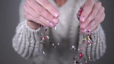 Kadın Elleri Parlak Tinsel Parıltıları, Bulanık Arkaplanda Konfeti. Parlak renkli bir konfeti kıvrılıyor ve bir hava girdabına düşüyor. Noel, yeni yıl, parti. Mutlu insanlar..