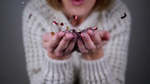 Happy Woman Blowing Shiny Kleurrijke Confetti Handen Een Wazige Achtergrond — Stockvideo