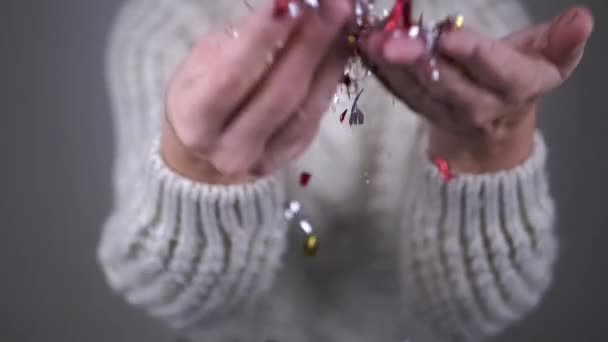 女性的手抛掷金银花 在模糊的背景下 闪闪发光的五彩斑斓的意大利面旋转着 落在一个空气漩涡中 圣诞节 快乐的人 — 图库视频影像