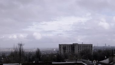 Terk Edilmiş Binanın Arkaplanına Karşı Gri Kümülüs Bulutları Taşımak. Şehrin kasvetli panoramik manzarası, fabrika ve rüzgarda sallanan ağaçlar. Sonbahar havası bulutlu. Ufuk. Doğa, kuşlar.