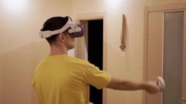 Oyun Denetimcili 3D Gözlüklü Bir Erkek Video Oyununda Bir Oda Oynuyor. Beyaz kasklı bir adam odada VR test cihazıyla el sıkışıyor. Sanal gerçeklik. Cihaz. Yapay zeka.