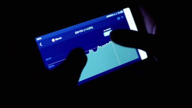 Gece Karanlık Oda 'da Cep Telefonu Uygulamasında Kripto Para Tablosu. Tüccar akıllı telefon ekranına parmağıyla dokunuyor. Dinamik, istatistik, büyüme, düşüş. Borsa. Gelecek fiyatı. Bitcoin.
