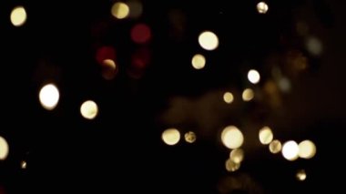 Yanıp sönen Noel Ampulleri, bulanık bir Noel Ağacı Arkaplanındaki Oyuncaklar. Göz kırpan altın ampuller ve çelenklerle odaklanmamış soyut bir arka plan. Bulanık bokeh. Noel süsü. Xmas.