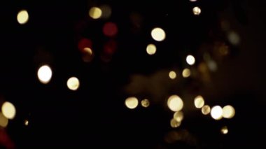 Yanıp sönen Noel Ampulleri, bulanık bir Noel Ağacı Arkaplanındaki Oyuncaklar. Göz kırpan altın ampuller ve çelenklerle odaklanmamış soyut bir arka plan. Bulanık bokeh. Noel süsü. Xmas.