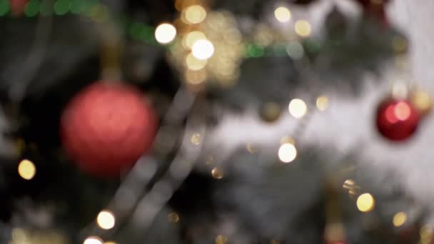 クリスマスライト電球をちらつき ぼやけたクリスマスツリーの背景におもちゃ 金色の斑点のある光 ガーランドを点滅させる焦点を当てていない抽象的な背景 ブラーボケ クリスマスの装飾 クリスマス — ストック動画