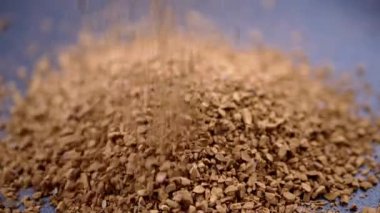 Instant Coffee Granules Fall and Scatter into a Heap on a Black Background. Slow motion. Close up. A stream of brown powder, gold particles, soluble coffee granules flies into a pile. Texture, light.