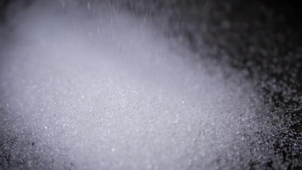Weiße Kristalle Aus Granulatzucker Fallen Zeitlupe Auf Einen Schwarzen Hintergrund — Stockvideo