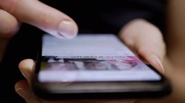 Kadın Parmaklar, Sosyal ağlardaki Haber Kaynağı 'nda bir cep telefonunda geziniyor. Yakın plan. Bir kadın akıllı telefondan mobil uygulamalara göz atıyor. Parmaklar ekrana değsin. Akıllı telefonda hayat..