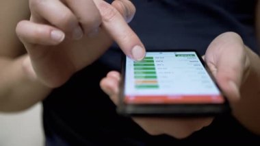 Yatırımcı, bir cep telefonunun dokunmatik ekranında kripto para biriminin fiyatını kontrol ediyor. Parmaklar akıllı telefonun ekranına değiyor. Mobil uygulama. Kripto para çiftleri, bitcoin. Borsa verileri. Büyüme, kriptonun düşüşü.