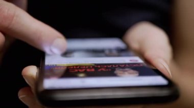 Kadın Parmaklar, Sosyal ağlardaki Haber Kaynağı 'nda bir cep telefonunda geziniyor. Yakın plan. Bir kadın akıllı telefondan mobil uygulamalara göz atıyor. Parmaklar ekrana değsin. Akıllı telefonda hayat..
