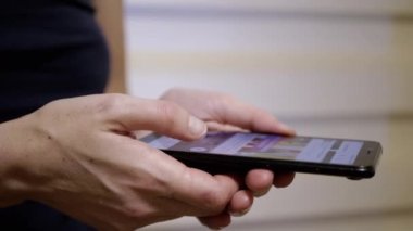 Kadın Parmaklar, Sosyal ağlardaki Haber Kaynağı 'nda bir cep telefonunda geziniyor. Yakın plan. Bir kadın akıllı telefondan mobil uygulamalara göz atıyor. Parmaklar ekrana değsin. Akıllı telefonda hayat..