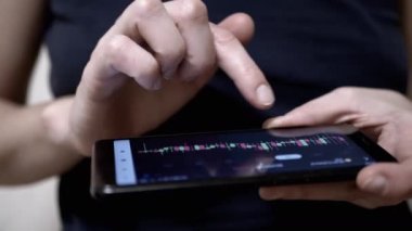 Mobil Telefon Dokunmatik Ekranında Şifreli Para Tablosu Gösteren Tüccar. Dişi parmaklar akıllı telefon ekranına dokunuyor. Mobil bir uygulamada şamdan şeması. Dinamik, borsa verileri.