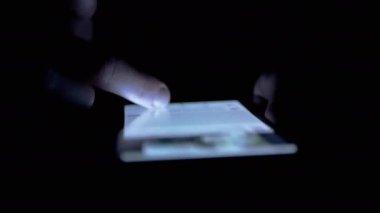 UKRAINE, KAMENSKOE, FEBRUARY, 2023: Sosyal ağlarda Kadın Parmakları Kaydırma Haberleri Bir Cep Telefonunda. Akşamları akıllı telefondan kız kıza mobil uygulama taraması. Karanlık odada parmaklar ekrana dokunur.