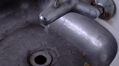 Akan Su Eski Paslı Musluktan Paslanmaz Çelik Lavabo 'ya dökülüyor. Lavaboda yemek artıkları. Ukrayna treninde kirli lavabo. Hareket ederken kamera hareketlerini sallıyor. Tuvalet vagonda..