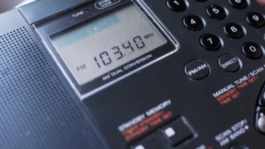 Kara Tozlu Modern Taşınabilir Radyo Alıcısı 'nda Frekans Aranıyor. Erkek parmakları düğmeye basarak FM dalgalarını arayın. İkili dönüşüm, elle akort, tarama istasyonu. Dijital ekran, kanal değişimi.