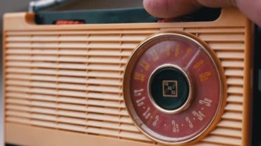Yakın plan, Erkek Parmaklar Eski Vintage Retro alıcıda Frekansı Ayarlar. Bant ayarı, FM dalgalarının frekans araması, dönüş kadranı. Manuel ayarlı eski sarı taşınabilir radyo alıcısı. 60 'lar, 70' ler.