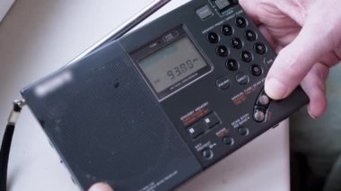 Kara Tozlu Modern Taşınabilir Radyo Alıcısı 'nda Frekans Bulmak. Erkek parmakları düğmeye basarak FM dalgalarını arayın. İkili dönüşüm, elle akort, tarama istasyonu. Dijital ekran, kanal değişimi.