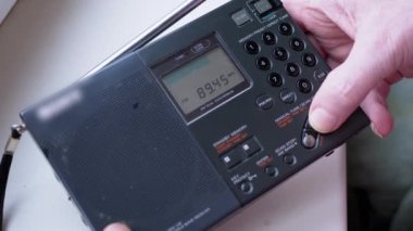 Kara Tozlu Modern Taşınabilir Radyo Alıcısı 'nda Frekans Bulmak. Erkek parmakları düğmeye basarak FM dalgalarını arayın. İkili dönüşüm, elle akort, tarama istasyonu. Dijital ekran, kanal değişimi.