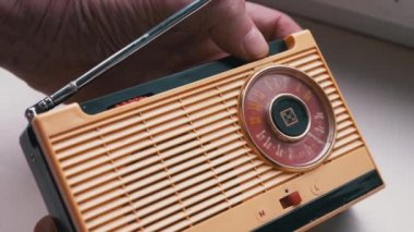 Yakın plan, Erkek Parmaklar Eski Vintage Retro alıcıda Frekansı Ayarlar. Bant ayarı, FM dalgalarının frekans araması, dönüş kadranı. Manuel ayarlı eski sarı taşınabilir radyo alıcısı. 60 'lar, 70' ler.
