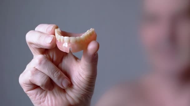 Homem Idoso Segurando Uma Dentadura Mandíbula Superior Mãos Sobre Fundo — Vídeo de Stock