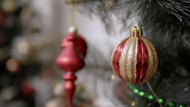 圣诞树上的圣诞球 背景模糊 灯火通明 靠近点红色闪亮的圣诞玩具树枝上的装饰品圣诞闪烁的灯 Bokeh 假日概念 — 图库视频影像