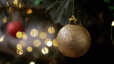 Altın Parlak Noel Balosu Işıkların Arkasında Spruce bir dalda asılı duruyor. Kapatın. Noel ağacı süsleme balosu. Yanıp sönen LED ışıkları olan bulanık bir arka plan. Noel süslemesi.