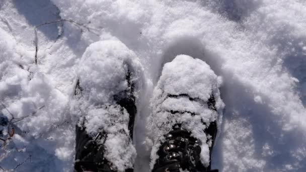 俯瞰全景的女人站在雪地里 抖落雪地上的黑色靴子 穿着雪地靴的脚靠得很近 在阳光下摇掉雪地上的雪鞋 下雪了慢动作 — 图库视频影像