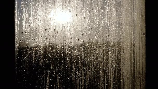 在金色落日的朦胧背景下 雨滴从玻璃上滚落下来 明亮的金色阳光照亮了窗户 新的水滴在轮廓中 — 图库视频影像
