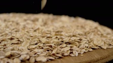 Siyah Dönen Arkaplanda Yulaf Ezmesi Yığını İçinde Düşen Kuru Yulaf Gevreği. Makro. Kapatın. Doku tahılı. Tahta tabak. Sağlıklı diyet kahvaltısı. Faydalı yemek. Fast food. Mısır, tahıl, buğday. Boşluğu kopyala.