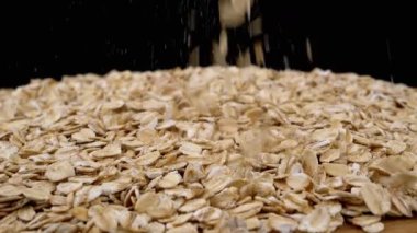 Siyah Dönen Arkaplanda Yulaf Ezmesi Yığını İçinde Düşen Kuru Yulaf Gevreği. Makro. Kapatın. Doku tahılı. Tahta tabak. Sağlıklı diyet kahvaltısı. Faydalı yemek. Fast food. Mısır, tahıl, buğday. Boşluğu kopyala.