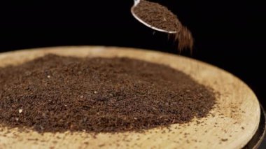 El, Yüzeydeki Çay Yığını Üzerine Bir Kaşıktan Dökülen Kurutulmuş Kara Çay Yaprakları. Siyah arka plan. Uzayı kopyala Kuru çay bolluğu. Şifalı bitki. Hareket. İçelim. Soyut. Doku. Tahta tabak..