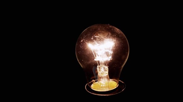 閉じます 黒の背景に輝くディム エジソン白熱電球 古いランプをオンとオフに輝く タングステンフィラメント 暖かい光だ ほこり エネルギー危機 停電だ — ストック動画