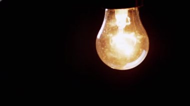 Kara Arkaplan 'daki Karanlık Oda' da sallanan titreşimli ampul. Yaşlı Edison tungsten parlıyor ve kapanıyor. Enerji krizi. Elektrik var. Elektrik kesintisi. Kesinti. Değiştir.