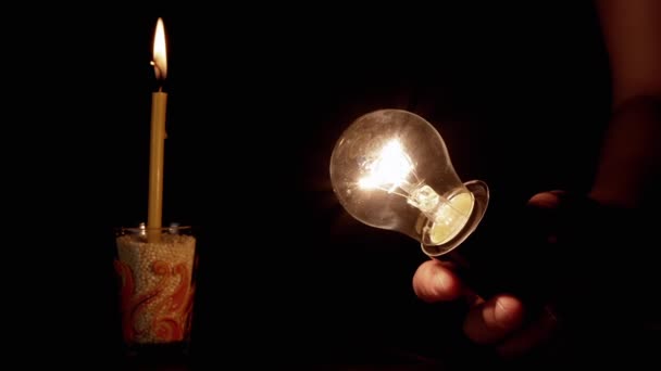 Рука Держащая Мигающую Лампочку Темной Комнате Фоне Горящей Свечи Вольфрамовая — стоковое видео