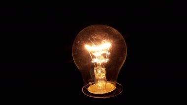 Yaklaş, Parıldayan Edison Siyah Arkaplanda Yanan Ampul. Eski tungsten lambası açılıp kapanıyor. Flaş. Merhaba. Ilık ışık. Yapı. İplik. Elektrik, enerji krizi. Kesinti.