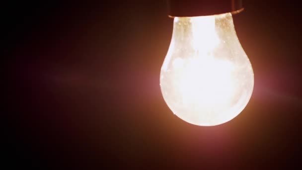 黒い背景の暗い部屋の中でスイングちらつき電球をぶら下げています 古いエジソンタングステン白熱灯が点灯し オフになっている エネルギー危機 電気だ 停電だ 停電だ — ストック動画