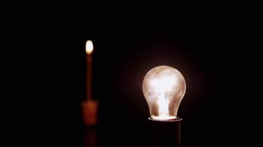 Yanan Mum 'un Kara Arkaplanı' ndaki Karanlık Oda 'da Parlayan Ampul. Edison tungsten parlak ampul ve sıcak ışık yandı. Enerji krizi. Elektrik var. Elektrik kesintisi. Kesinti. Kapalı.
