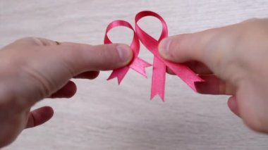 Kadın Elleri Ahşap Beyaz Arkaplanda İki Pembe Kurdele Gösteriyor. Kapatın. Göğüs kanseri sembollü bir el. Kanser bilgisi. Umut. Ekim ayı. Uluslararası AIDS, Kanser Günü. Hastalık Bilinci.