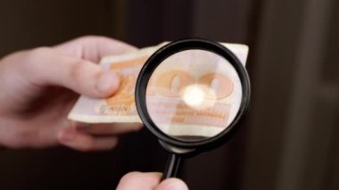 Eski Ukrayna Parasını İnceleme, Büyüteçle Kuponlar. Eller yakın çekim. Vücut parçası. Çocuk işaretlere, sembollere, banknotlardaki rakamlara bakıyor. Hobi olarak. Gri arka plan bulanık. Koleksiyon.