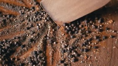 Renkli Dönen Arkaplan 'da Tahta Spatula ile karıştırılmış Hint Baharatları. Kapatın. Baharatlı biberler, kurutulmuş otlar, dereotu, paprika, zerdeçal, kekik. Doku, şekil. Palet kurutulmuş baharat..