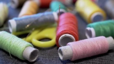 Yakın plan, Gri Arkaplanda İplik Döndüren Renkli Dikiş Spikerleri. İğne, makas. Dikiş takımı. İş yeri. Dikiş, dikiş atölyesi, el yapımı, dikiş işi kavramı. Döngü. Terzilik.