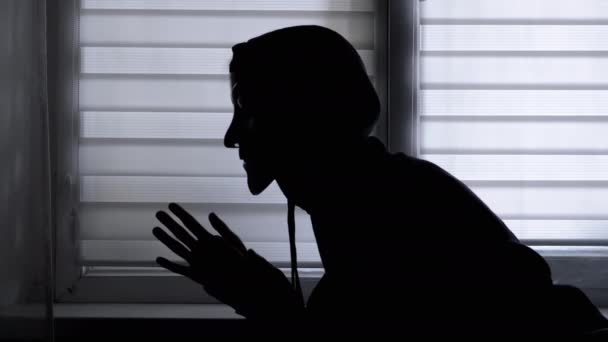 Maskeli Başlıklı Adam Pencerenin Yakınındaki Karanlık Bir Odada Ellerini Ovuşturuyor — Stok video