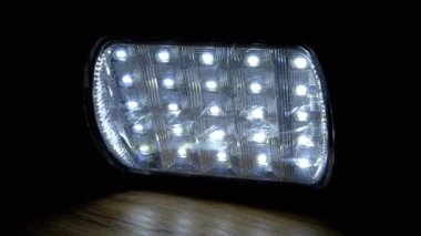 Led Ampullü El Feneri Karanlık Oda 'daki Ahşap Masayı Aydınlatıyor da dahil. Kapatın. Taşınabilir spot ışıkları ve enerji tasarrufu ampulleri. Enerji krizi, elektrik kesintisi, evde elektrik tasarrufu. Savaş.