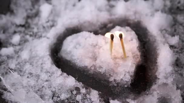 在一个心形湿雪岛上 燃烧着两个火柴盒 在雪地融化的背景下 一对恋人坠入爱河的戏剧性的爱情故事 友谊的概念 — 图库视频影像
