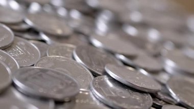 Yakın plan, Dönen Arkaplanda Bir sürü gümüş sikke. Para geçmişi. Ukrayna kuruşları, kopekler. Hareket ediyor, dönüyor. Finansal kriz, birikim, birikim. Ukrayna amblemi, damga.