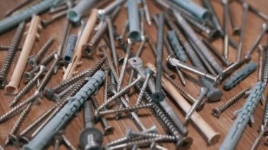 Bir sürü Paslanmaz Çelik Fastener döner ahşap arka planda. Kapatın. Bir sürü galvanize edilmiş, kendi kendine dokunabilen vida plastik perdeler, vidalar, cıvatalar ve çamaşır makineleri. Seçici odak.