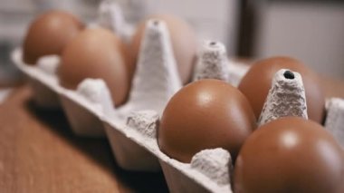 Yaklaş, Tahta bir arka planda karton tepside taze tavuk yumurtası. Makro. Yumurta tepsisinde, kahverengi kabuklu çiğ yumurta. Doku. Seçici odaklanma. Üst Manzara. Görüldü. Işık. Organik ürün.