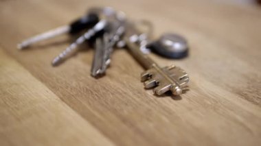 Yakın plan, Dairenin Demir Anahtarları Dönen Ahşap Arkaplan. Doku. Seçici odaklanma. Üst Manzara. Arka plan bulanık. Emlak, ev ve araba satın alma kavramı. Yavaş dön. Çal.