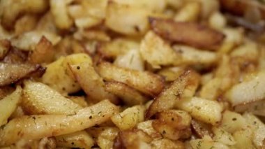 Kızarmış patates ve altın hamurlu kızartma tavası ve döner arka plan. Kapatın. Doku. Ev mutfağında pişirilmiş baharatlarla yağda kızartılmış patates kızartması. Yan görüş. Yavaş çekim.