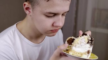 Yaklaş, Yüz Çocuk Kremalı Büyük Pasta Yiyor ya da Brownie. Tatminsiz çocuk ağzını açıyor, tatlı bir tatlıyı kaşıkla yiyor. Arka plan bulanık. Sağlıksız yiyecekler. Aşırı yemek. Doğum günü.